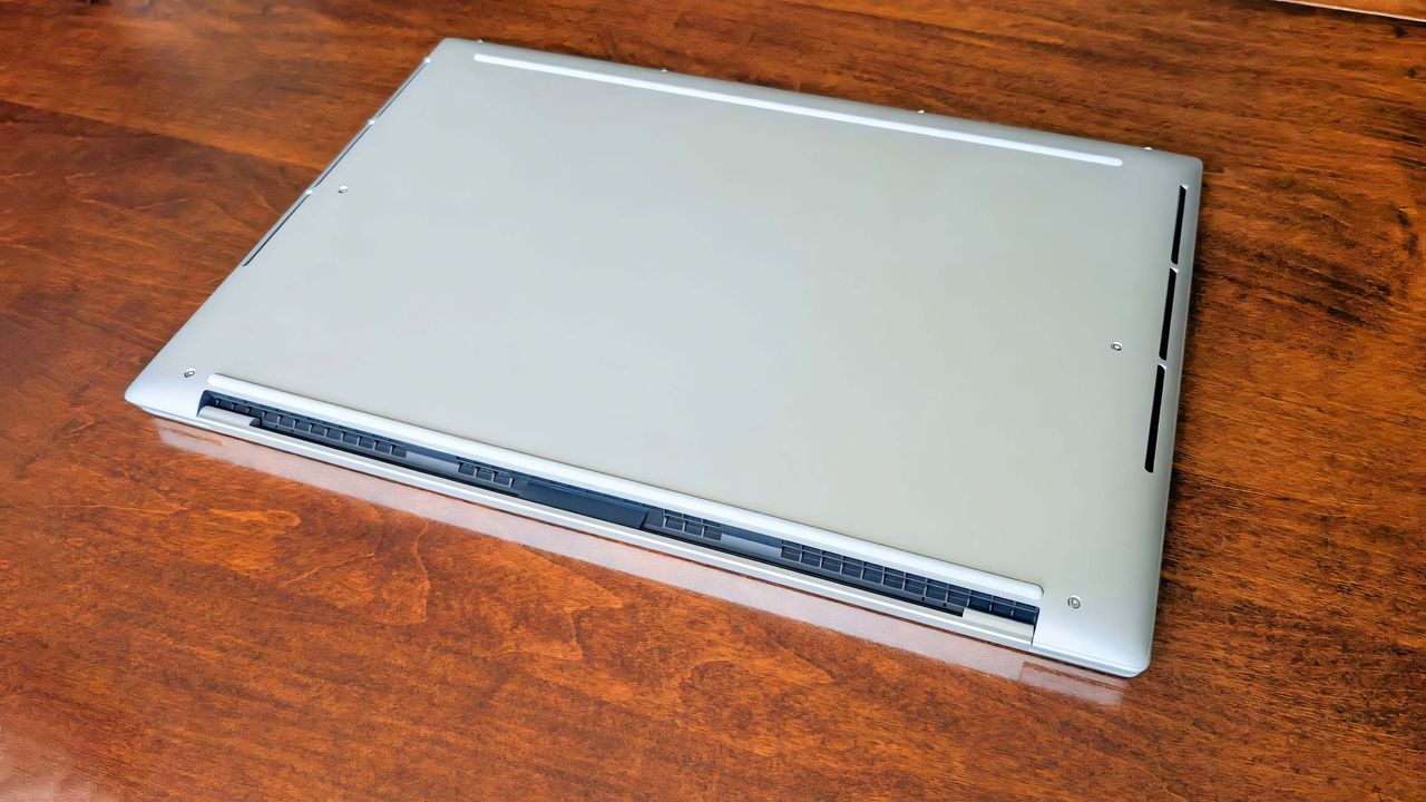 The Dell 16 Premium underside facing up on a wooden table.