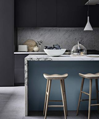 A grey kitchen with colour blocks paintwork in light blue, a marbled breakfast bar and bar stools.