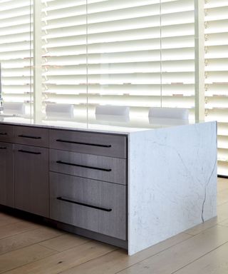 A modern neutral kitchen with a waterfall countertop