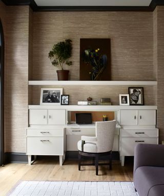 office with neutral wallpaper, white desk and shelves, purple sofa