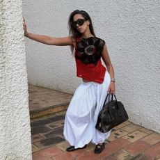 Hanna MW wearing white genie pants with a crochet red-and-black top. 