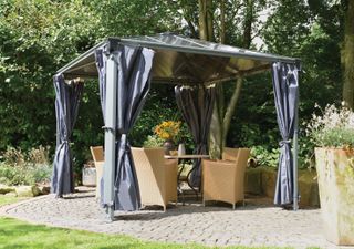 outdoor dining area underneath a gazebo with curtains