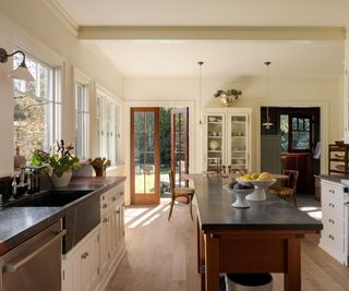 vintage style kitchen with dark island and white cabinets and wooden floors