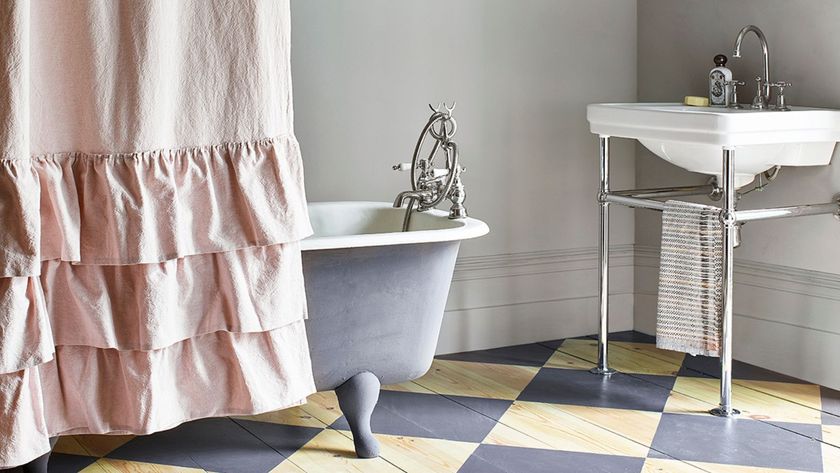 A vintage-style bathroom with a freestanding roll-top bath, ruffled fabric shower curtain, classic basin and bold checkerboard flooring for a characterful look.