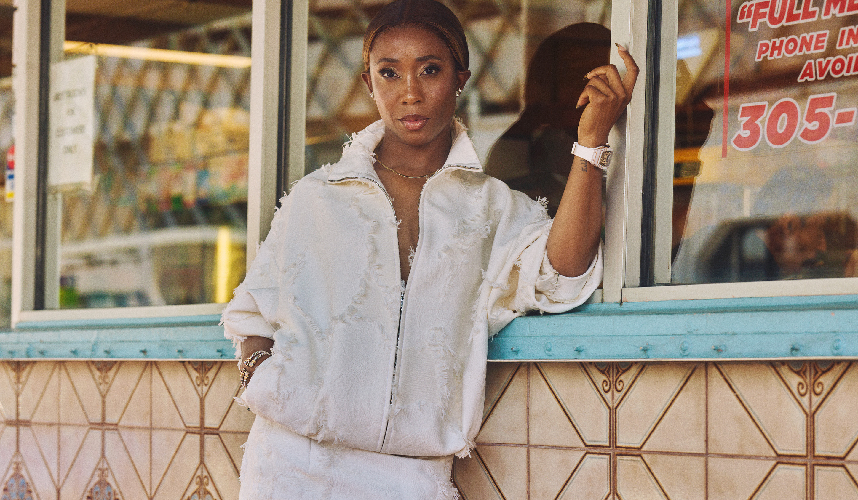 Shelly Ann Fraser Pryce wearing a white hoodie next to a storefront