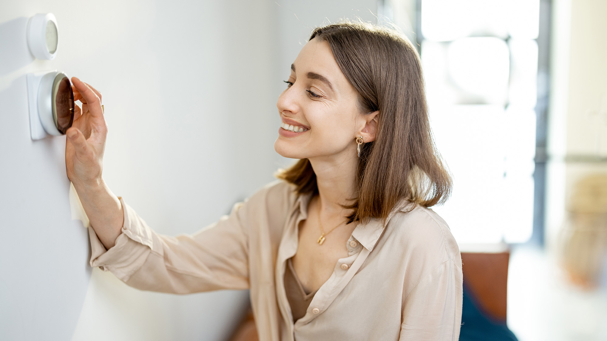 Woman adjusting smart thermostat