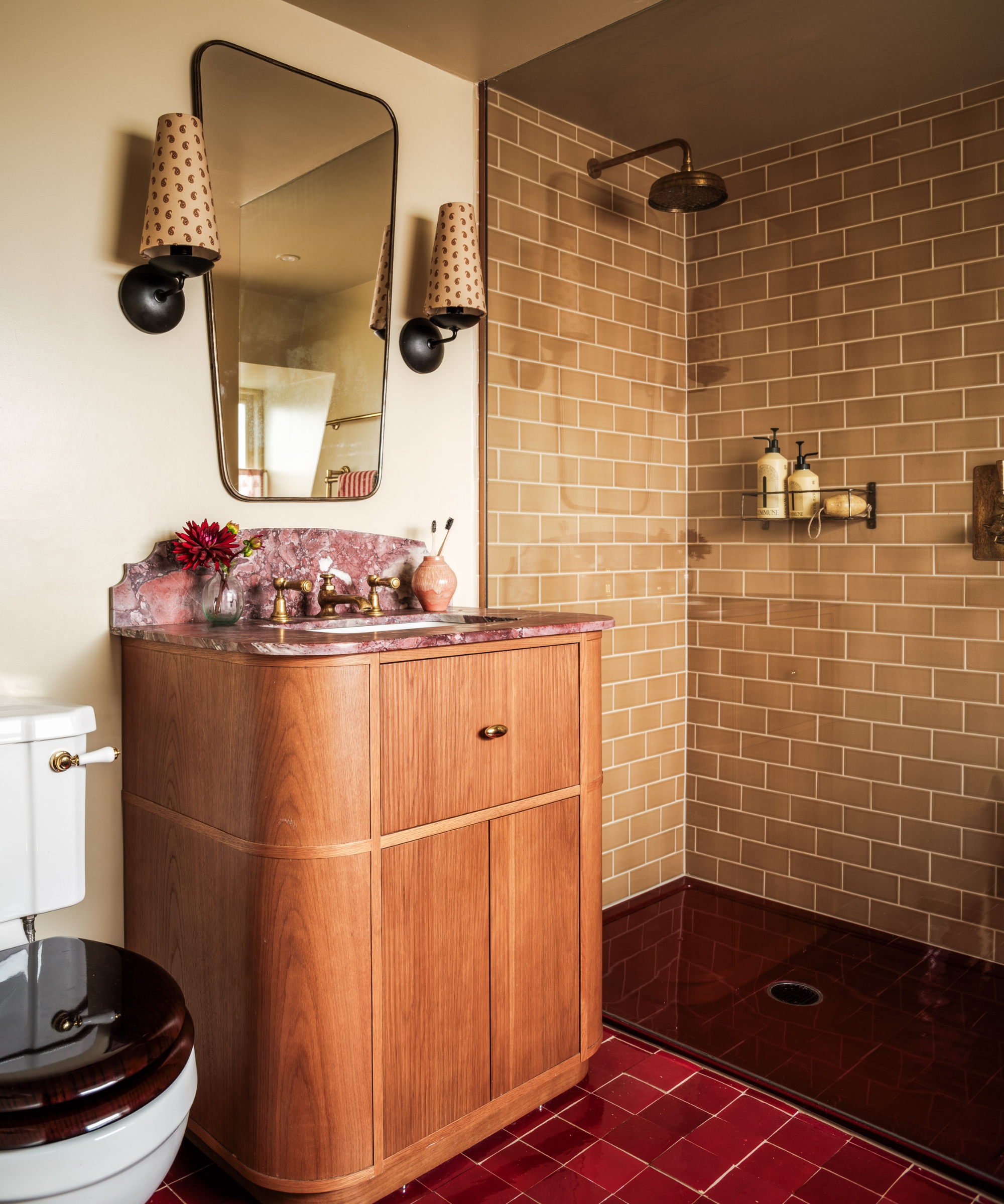 A small shower toom with a curved wooden vanity, warm beige shower wall tiles, and a black shower floor