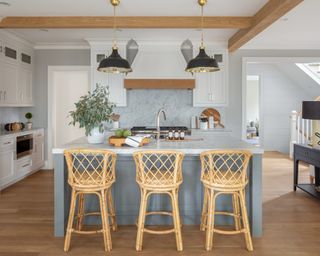 A modern farmhouse-style kitchen with grey island, marble backsplash and bamboo bar stools