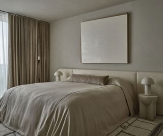 Primary bedroom in greige tones with linen sheets and focal canvas above bed
