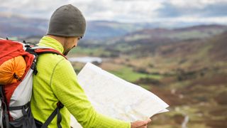 Man reading a map while hiking in a valley