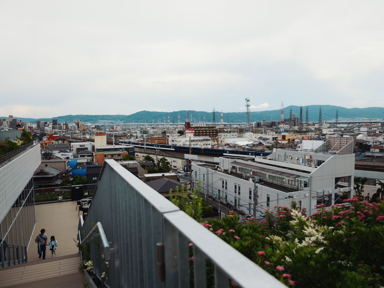 Wide city view over Osaka with railway tracks and distant hills.