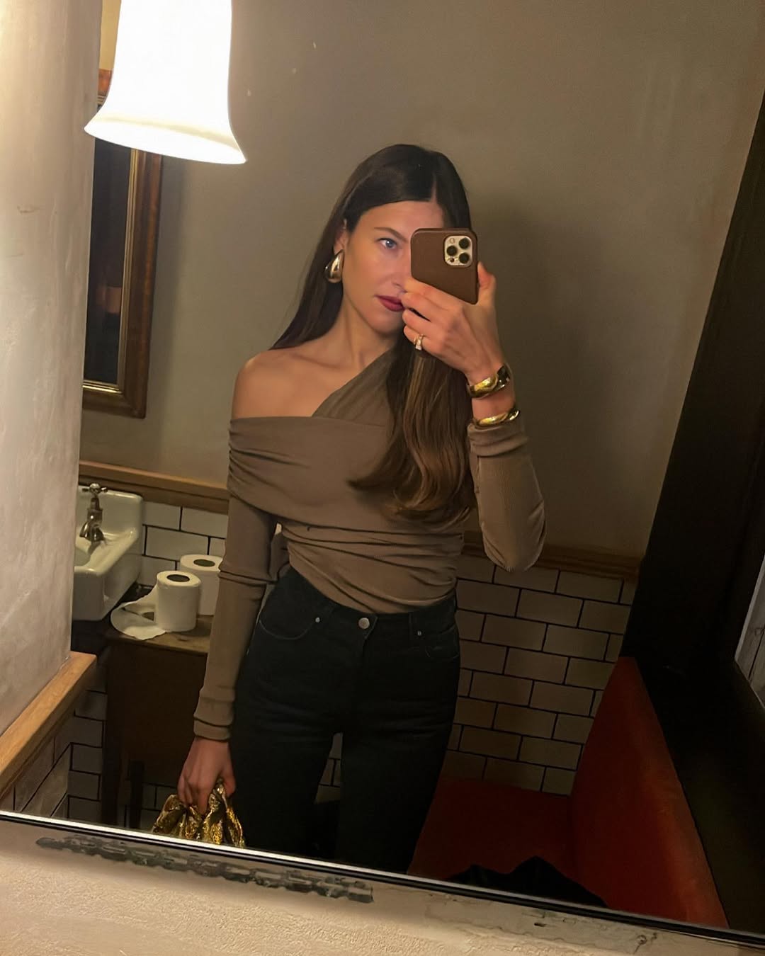 @saraloura wearing indigo skinny jeans and a khaki green off the shoulder top in a bathroom