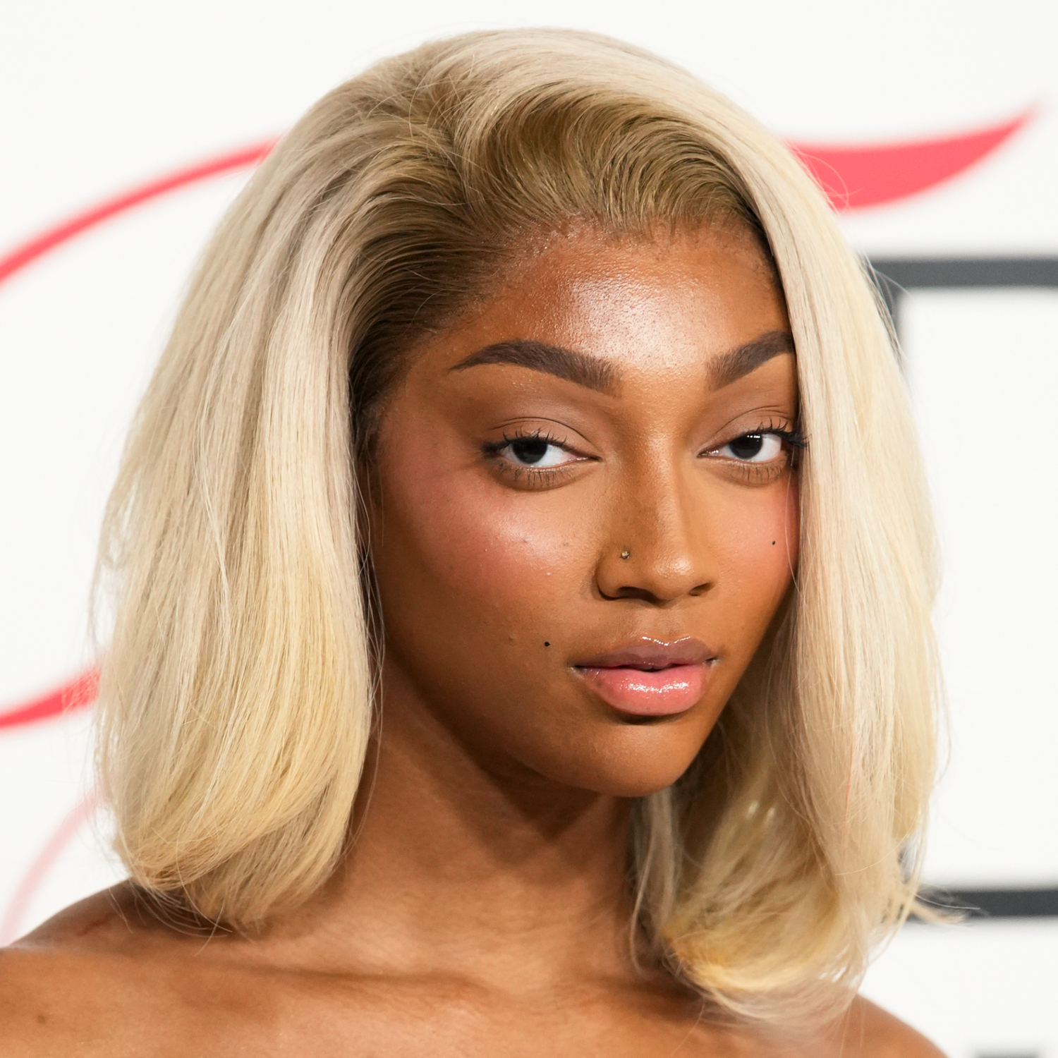 Angel Reese wearing soft lashes with blonde hair facing the camera