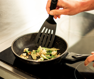 A black plastic spatula in a frying pan