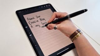 A shot of someone holding the Adonit Star stylus up against an iPad screen as they write
