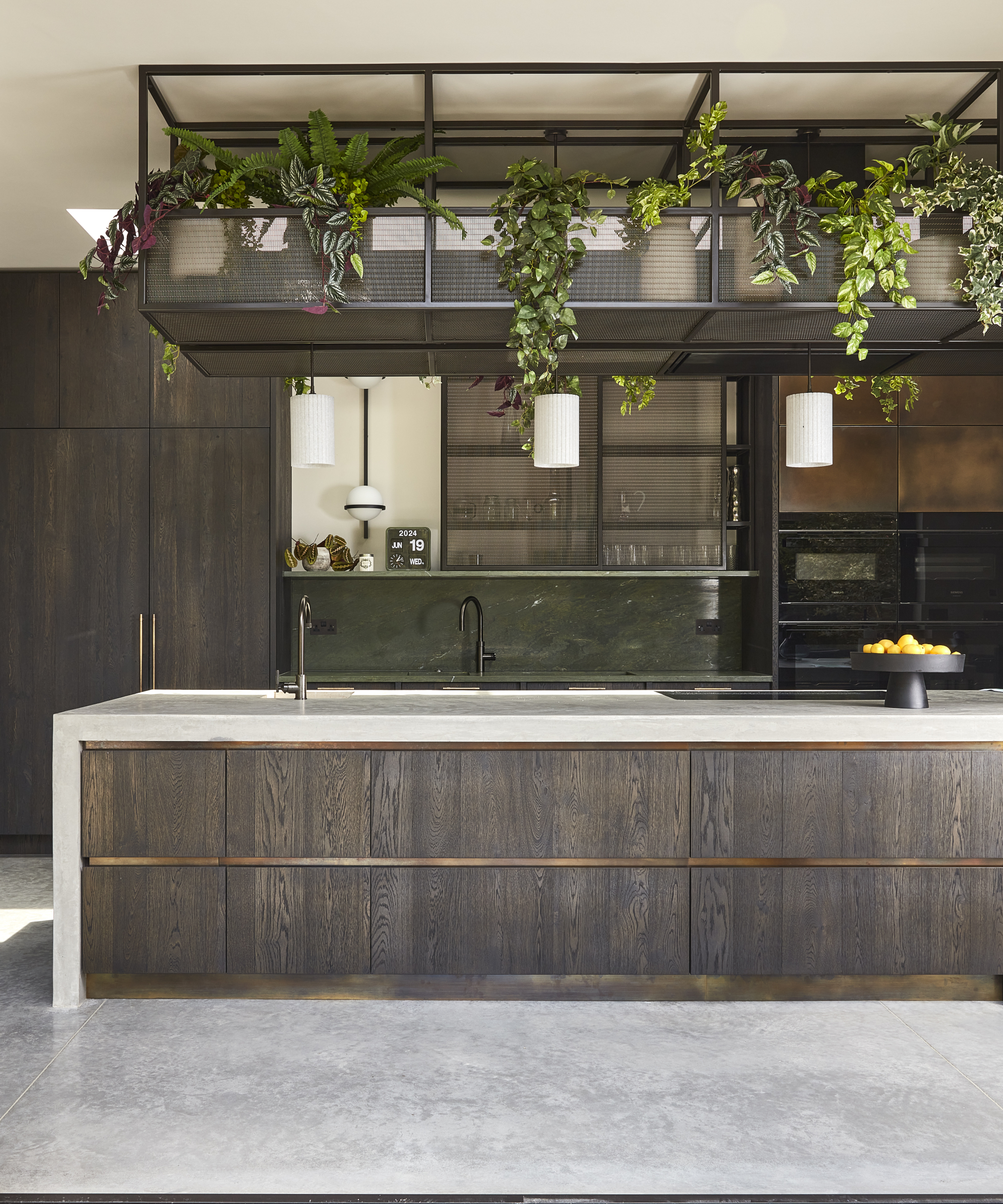 dark wooden kitchen with metal gantry above large kitchen island with sink