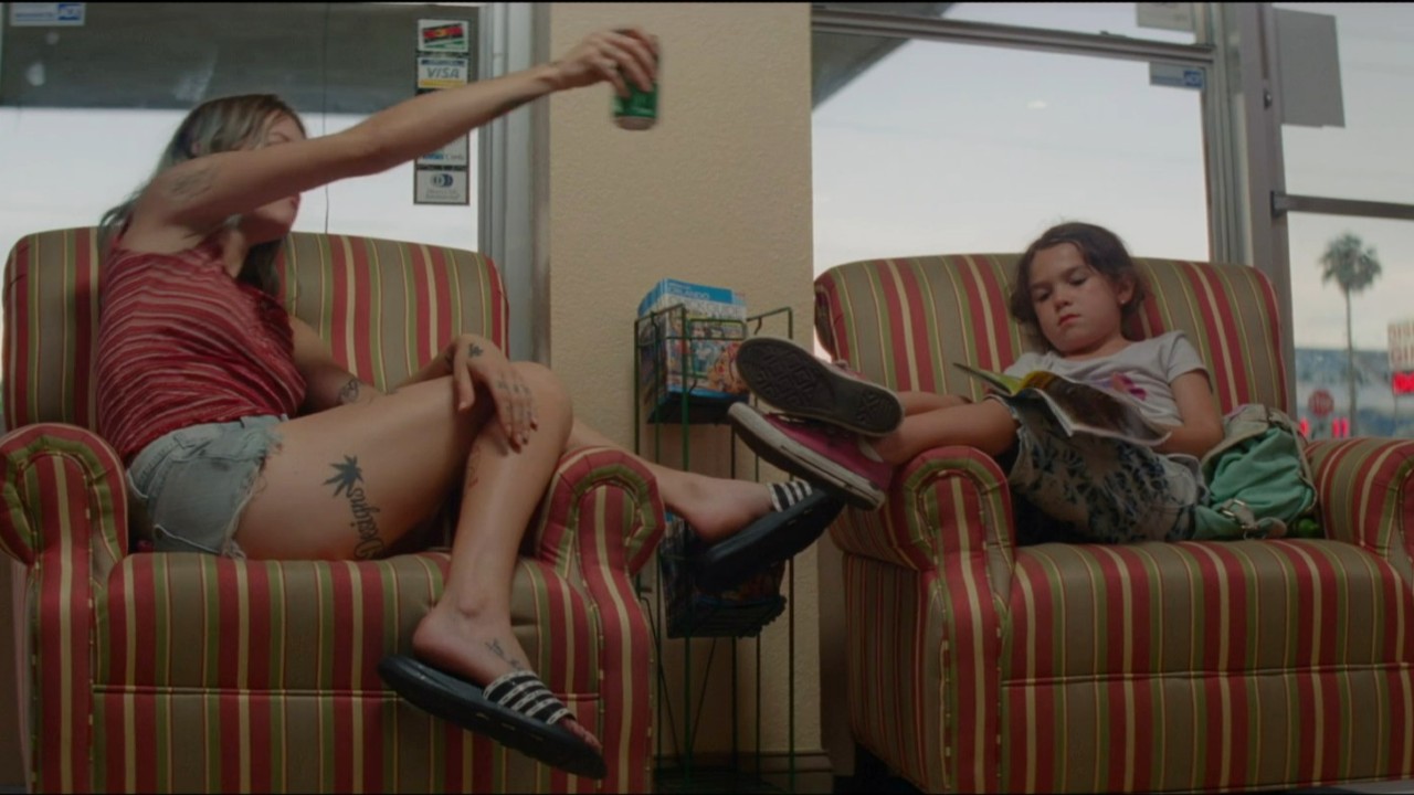 Brooklynn Prince reading while Bria Vinaite plays with a can in The Florida Project.