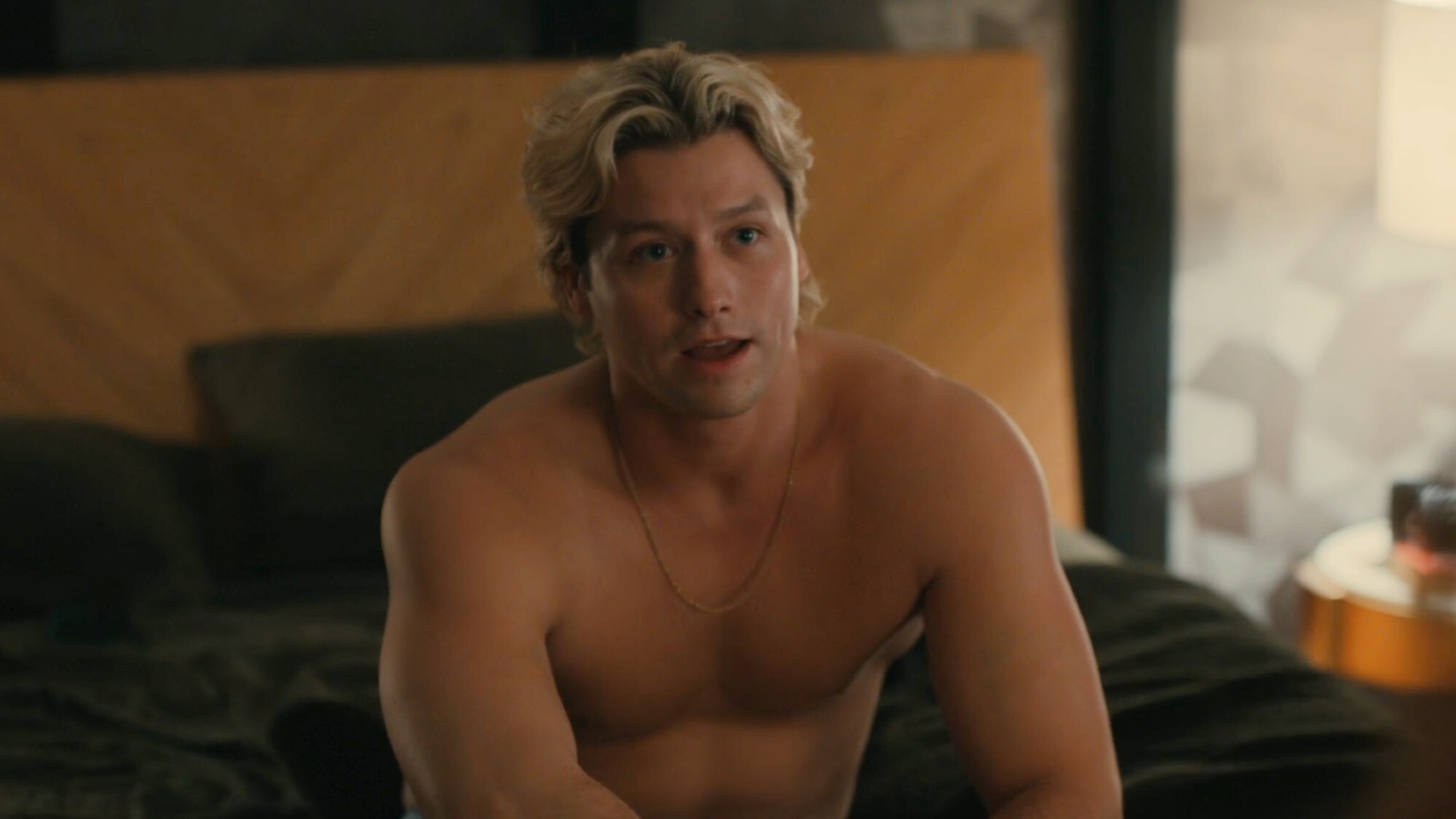 Stephen Kalyn as Dean Di Laurentis shirtless and sitting on a hotel bed with his mouth open in Off Campus