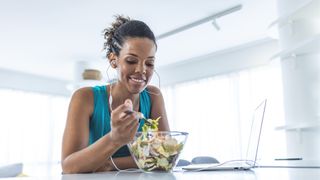 Woman having breakfast and using laptop