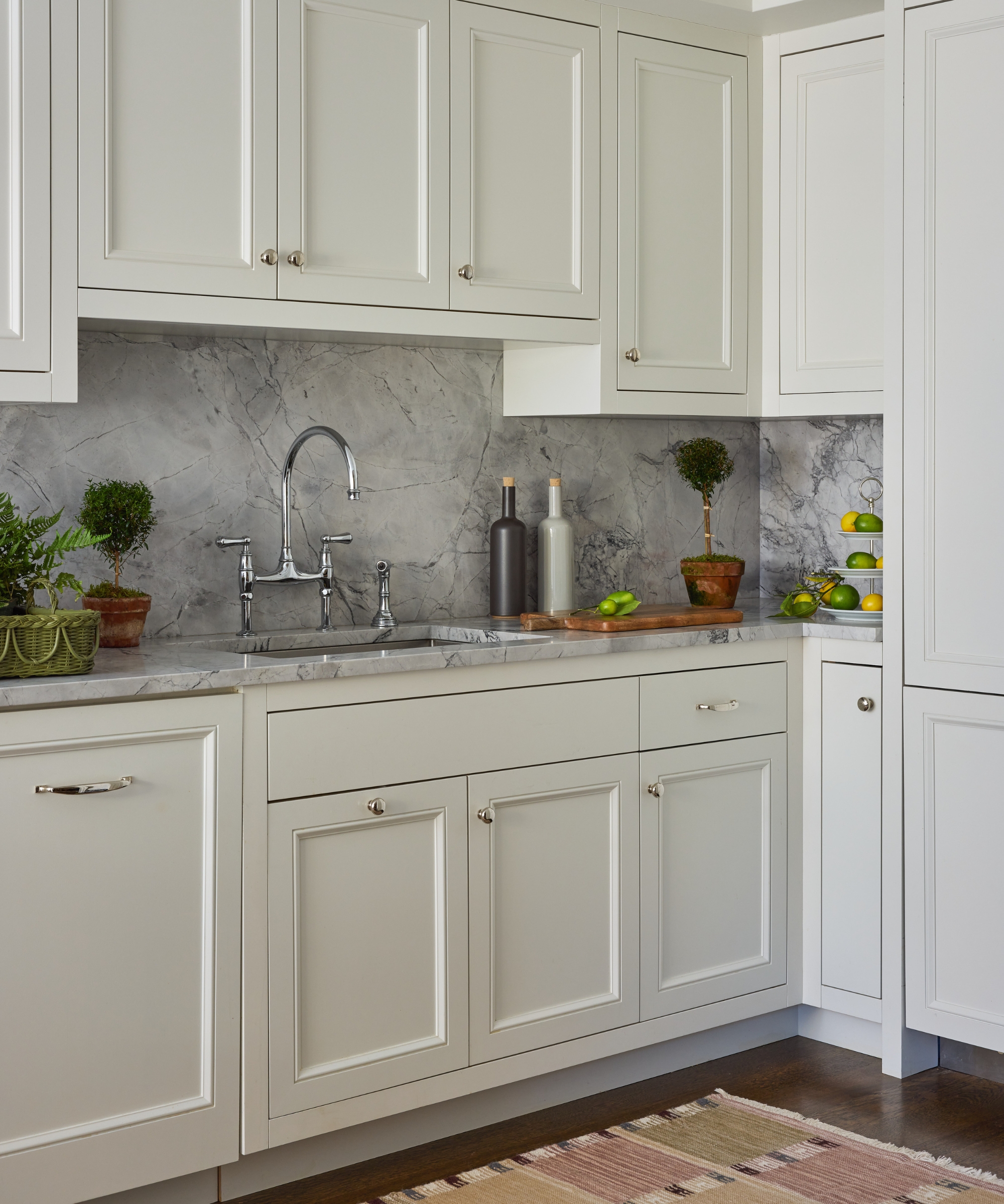 Compact white kitchen with grey marble backsplash, Shaker cabinetry, chrome tap and a vintage striped runner.