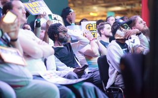 Ryan Hart reacts to a moment in a match whilst Profluke covers his face with a sign in despair.