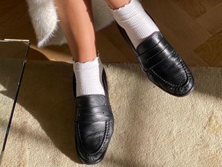 stylish scandinavian woman wearing white ruffled ankle socks and classic black loafers