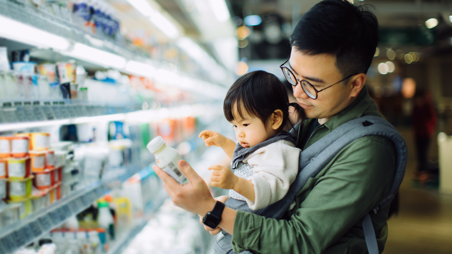 image shows a man shopping for milk with his daughter