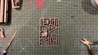 A cutting mat with various tools on it, along with a miniatures sprue