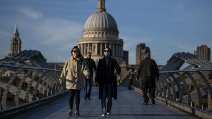 Pedestrians walk across the Millennium Bridge in front of St Pauls Cathedral.