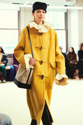 model wearing a yellow duffle coat on the altuzarra fall 2024 runway