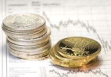 Stacks of silver and gold coins next to a stock market graph