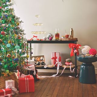 large christmas tree with presents underneath, next to a bar cart filled with drinks and glasses