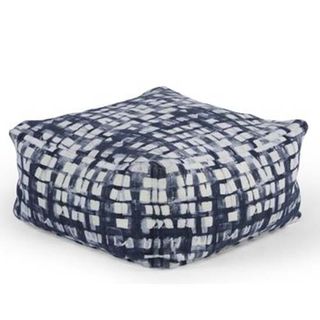 A cube shaped pouffe with a blue and white geometric tie-dyed pattern.