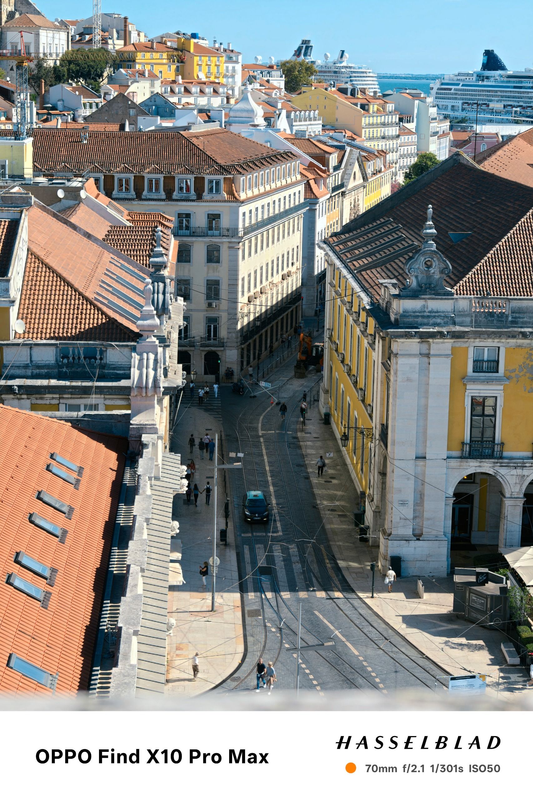 High-angle view down a Lisbon street with tram tracks running between historic buildings.