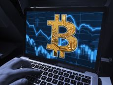 Laptop with Bitcoin B symbol on a background of financial market data in blues and orange.