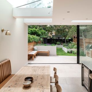 open plan kitchen diner with leather banquette seating and a skylight and sliding doors leading out into the garden