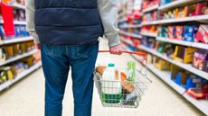 Man holding shopping basket with groceries in supermarket