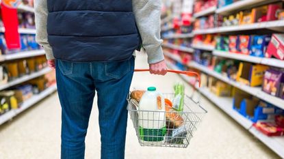 Man holding shopping basket with groceries in supermarket