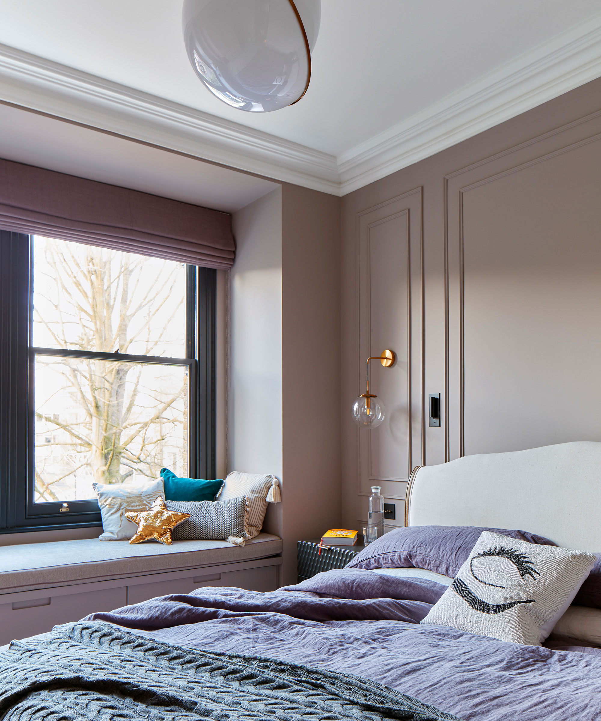 small pink bedroom with dark grey painted sash window and window seat