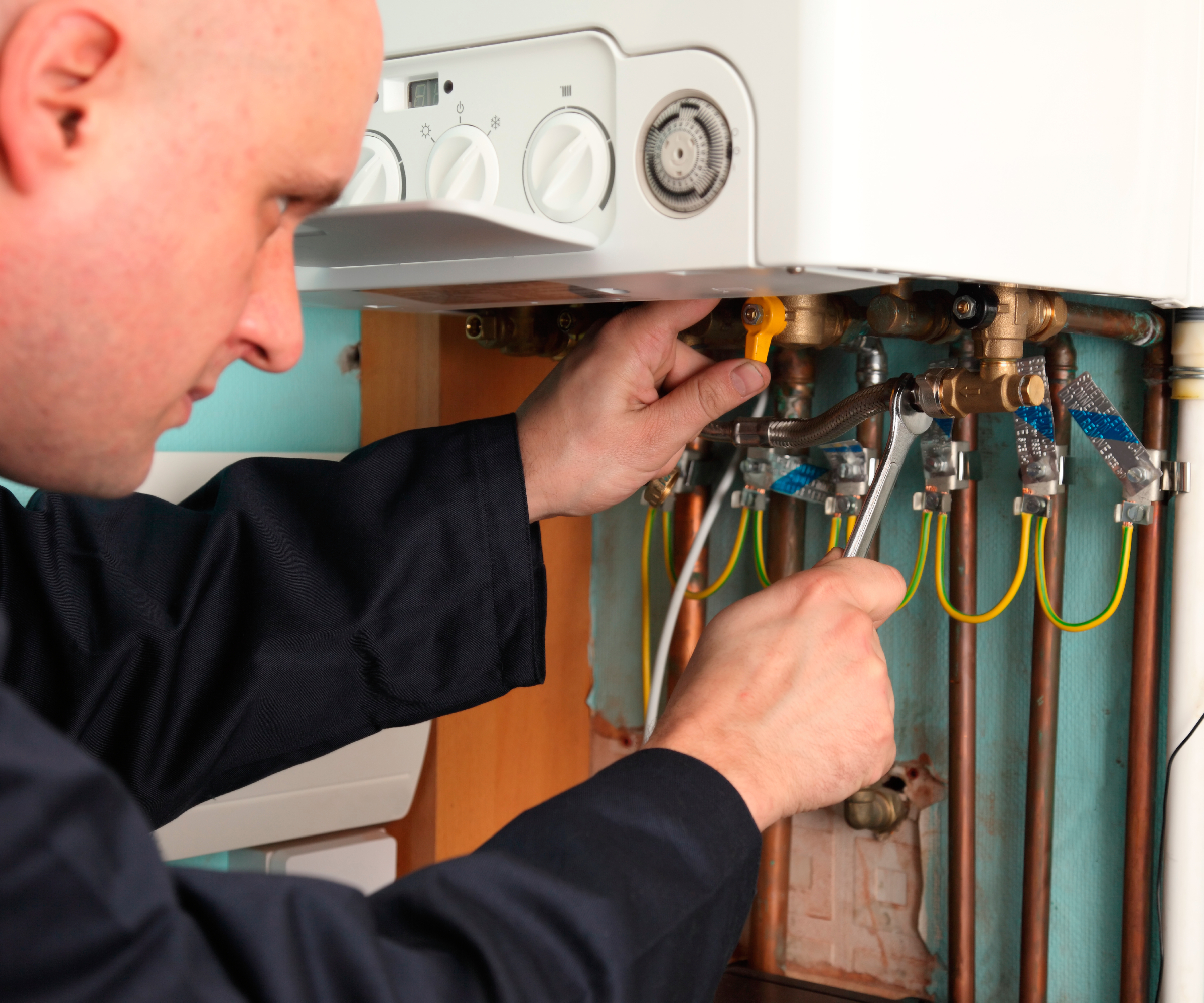 plumber adjusting pipes below boiler
