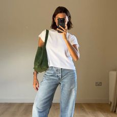 Influencer Marianne wears a basic white tee and light-wash jeans with a suede green tote. 