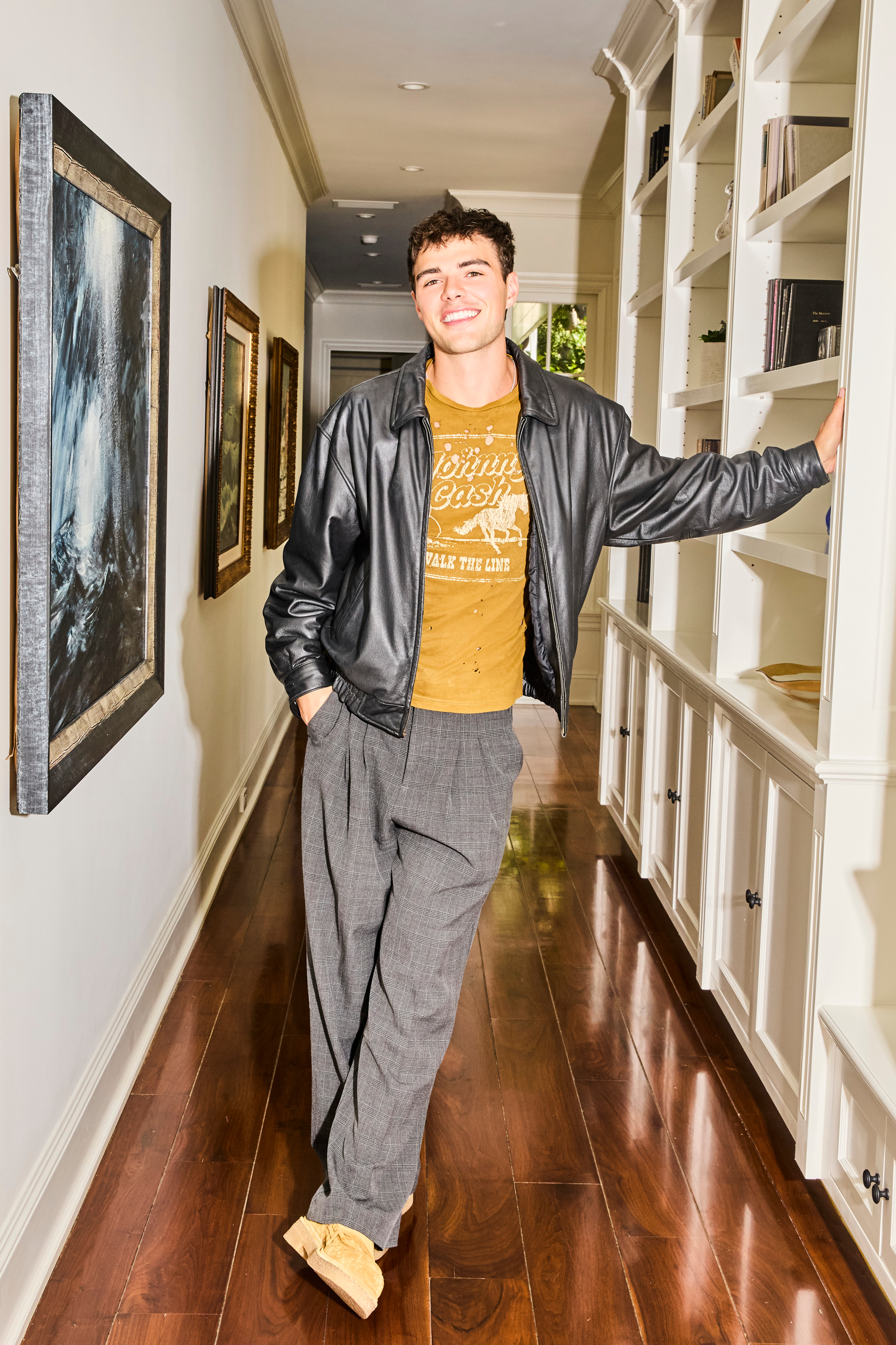 sterling retzlaf in a t-shirt and leather jacket standing in a hallway in a promotional shot for calabasas confidential