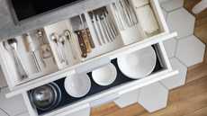 Top view storage organization plate dishes in wooden drawer at modern minimalistic kitchen in Nordic style. Placing crockery in cupboard use Konmari keeping method. General cleaning, tidying up