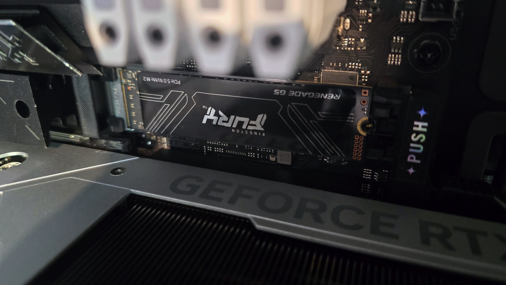 A photo of an 8 TB Kingston Fury Renegade G5 SSD, installed in a gaming PC&#039;s main M.2 slot above the graphics card