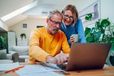 Happy senior couple bonding while using laptop at home. Elderly husband and wife on laptop.