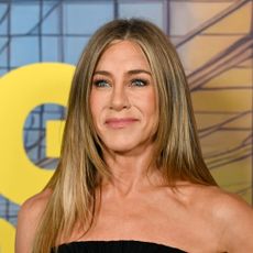 Jennifer Aniston stands in front of blue and yellow background