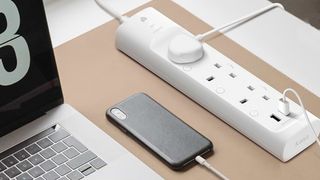 TP Link Kasa KP303 smart plug on a desk with a computer plugged in