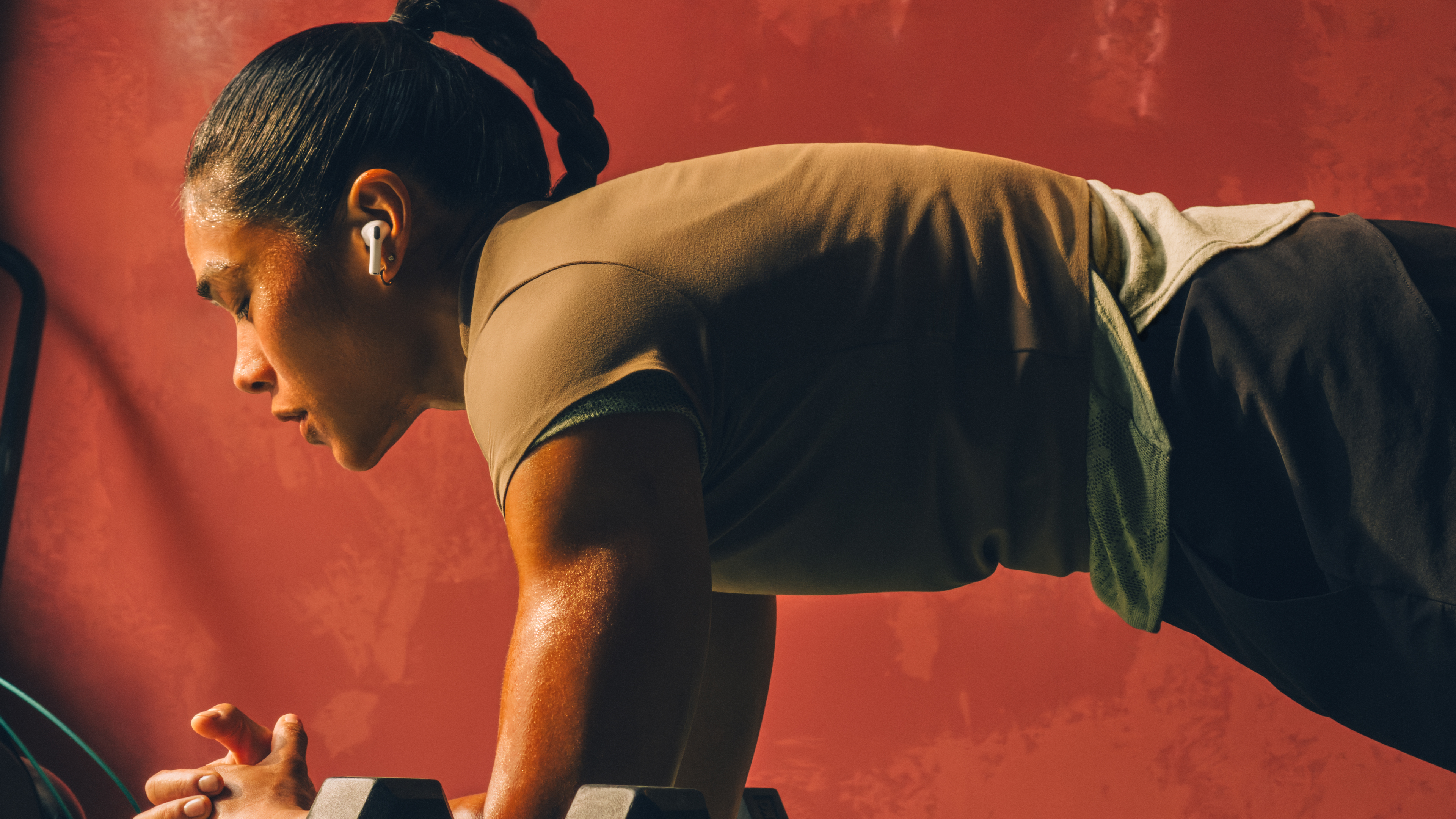 A woman doing a plank exercise while wearing AirPods Pro 3