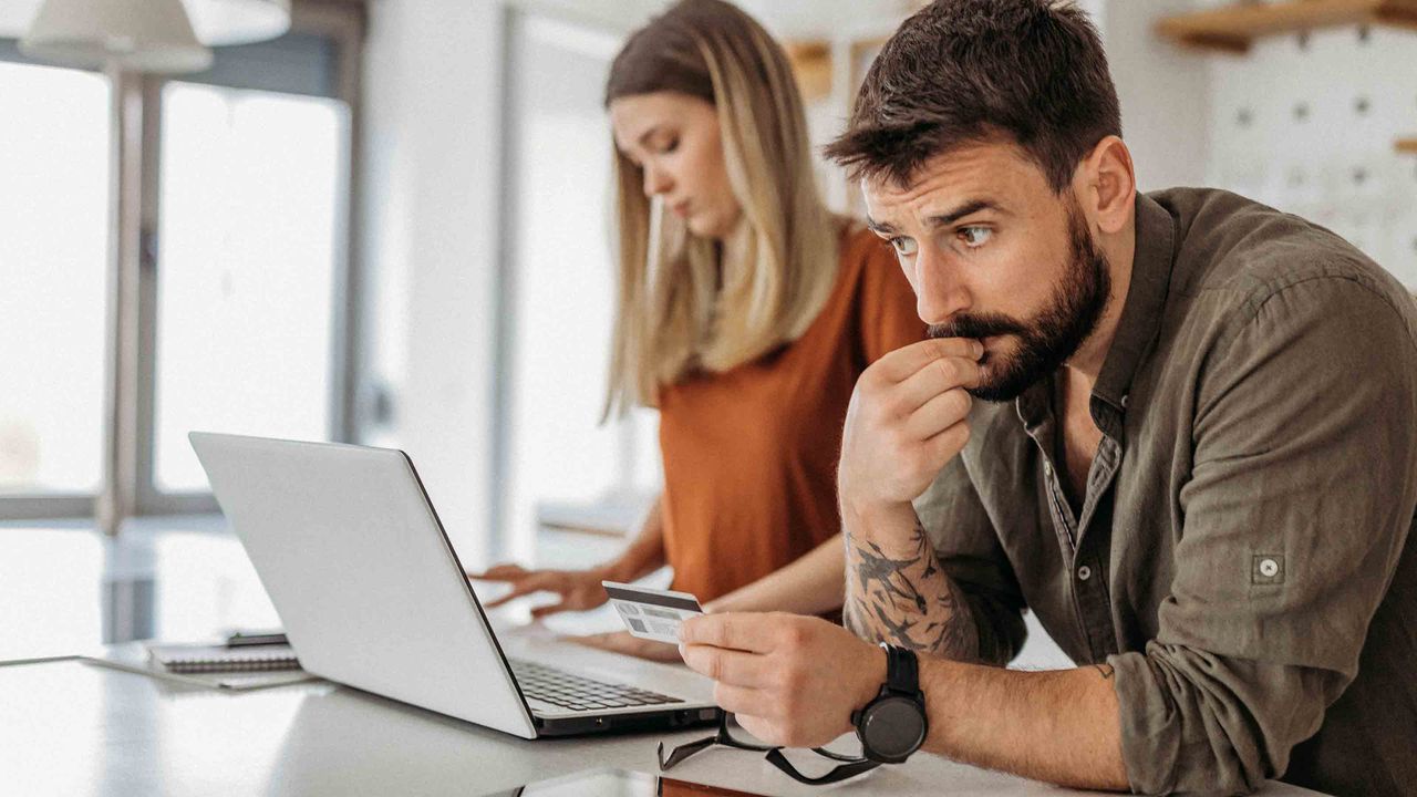 Young couple in kitchen with laptop and credit card