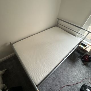 The Emma NextGen Premium mattress on a metal bedframe in a room with a grey carpet